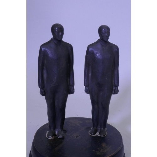 111 - A pair of cast iron figures of standing men, mounted on a wood base and under a glass dome, 20cm hig... 