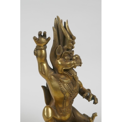 144 - A Tibetan bronze of a wrathful beast seated on a pig, double vajra mark to base, 22cm high