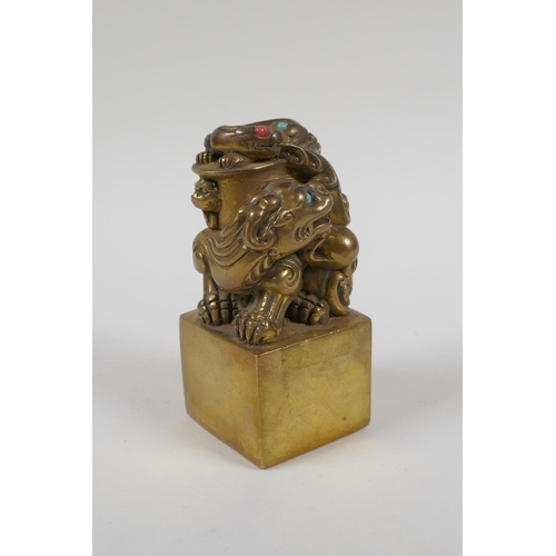 165 - A Chinese filled gilt bronze seal, the knop in the form of kylin inset with coral and turquoise bead... 