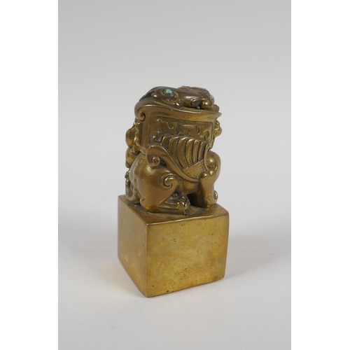 165 - A Chinese filled gilt bronze seal, the knop in the form of kylin inset with coral and turquoise bead... 