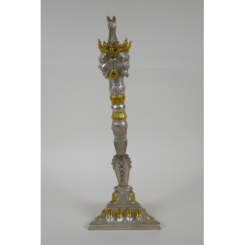 195 - A Tibetan white metal phurba and stand, with gilt highlights, the hilt decorated with wrathful masks