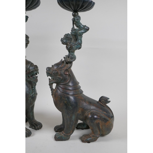 213 - A pair of oriental bronze pricket candlesticks in the form of kylin, 46cm high