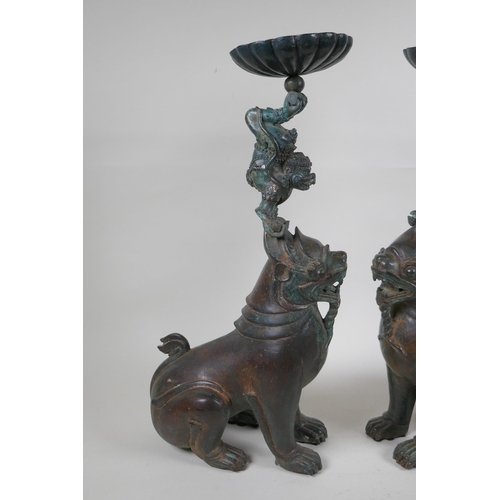 213 - A pair of oriental bronze pricket candlesticks in the form of kylin, 46cm high