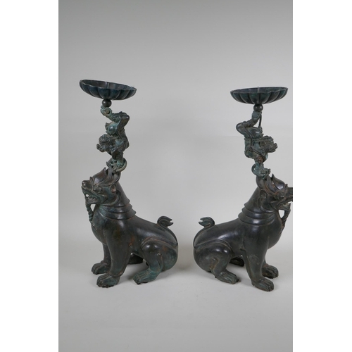 213 - A pair of oriental bronze pricket candlesticks in the form of kylin, 46cm high