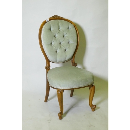 1061 - A Victorian walnut nursing chair with carved back, raised on cabriole supports