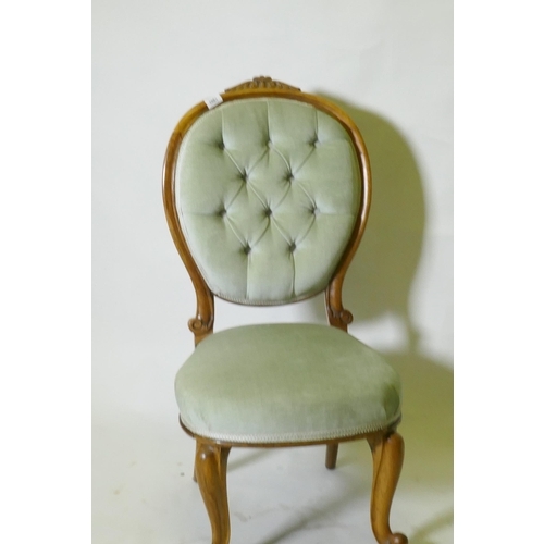 1061 - A Victorian walnut nursing chair with carved back, raised on cabriole supports