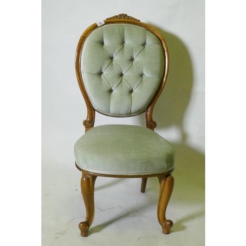 1061 - A Victorian walnut nursing chair with carved back, raised on cabriole supports