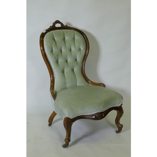 1052 - A Victorian carved walnut nursing chair, raised on cabriole supports with brass castors