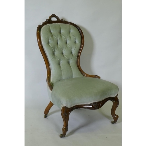 1052 - A Victorian carved walnut nursing chair, raised on cabriole supports with brass castors