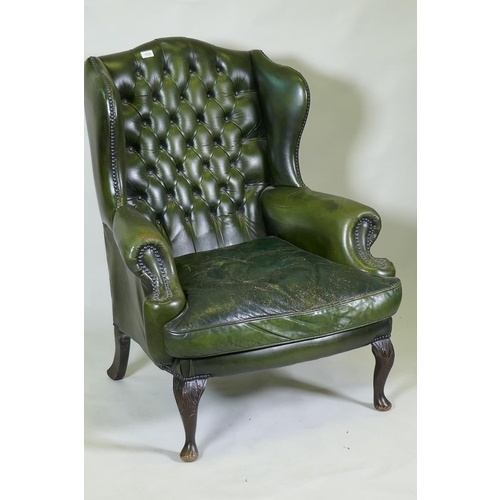 1024 - A green leather buttoned wingback armchair