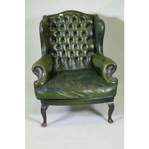 1024 - A green leather buttoned wingback armchair