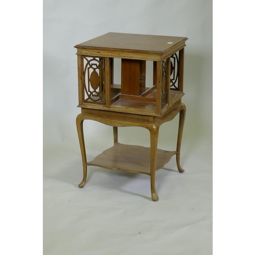 1007 - Edwardian walnut revolving bookcase with pierced fret decoration, raised on cabriole supports, unite... 