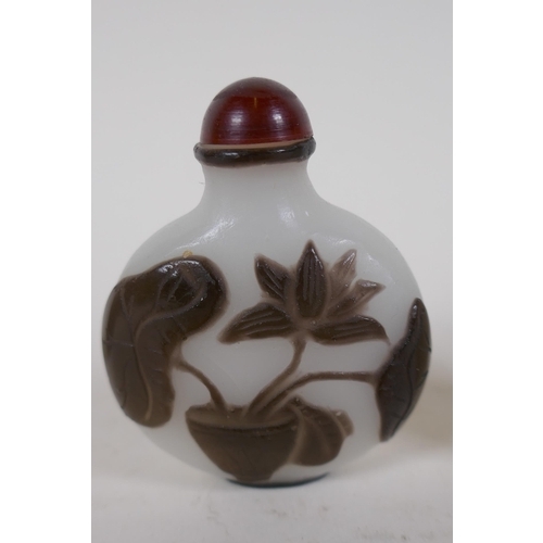 343 - A Peking glass snuff bottle with carved decoration of a potted lotus flower, and a carved hardstone ... 