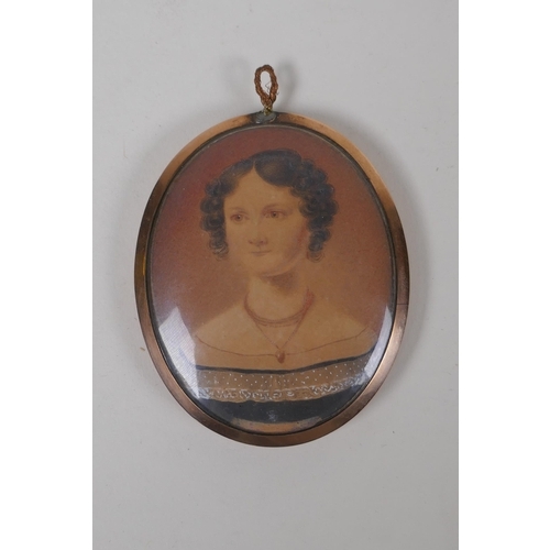 809 - An early C19th miniature watercolour portrait of a lady in a rose metal pendant frame, with plaited ... 