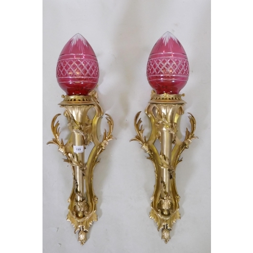 199 - A pair of ormolu wall sconces of trumpet form with leaf swags and cranberry glass shades, 63cm high