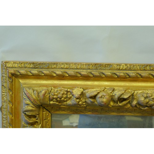 863 - A mid C19th giltwood and composition picture frame, with moulded fruit decoration, fitted with a mir... 