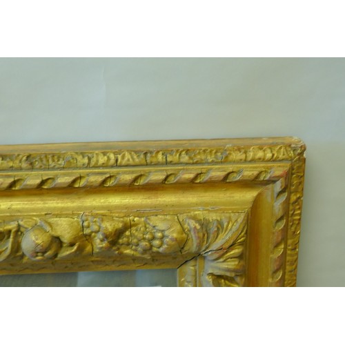 863 - A mid C19th giltwood and composition picture frame, with moulded fruit decoration, fitted with a mir... 