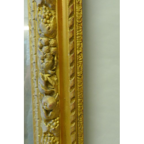 863 - A mid C19th giltwood and composition picture frame, with moulded fruit decoration, fitted with a mir... 