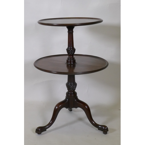 1017 - A Georgian mahogany two tier dumb waiter, raised on carved and turned column and tripod supports wit... 