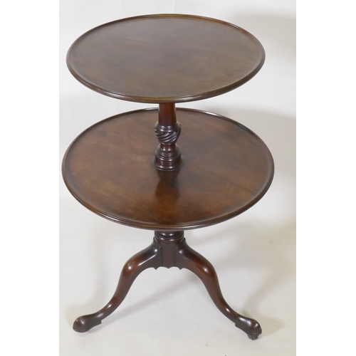 1017 - A Georgian mahogany two tier dumb waiter, raised on carved and turned column and tripod supports wit... 