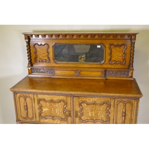 1039 - An early C20th oak Jacobean style mirror back sideboard, with two cupboards opening to reveal shelve... 