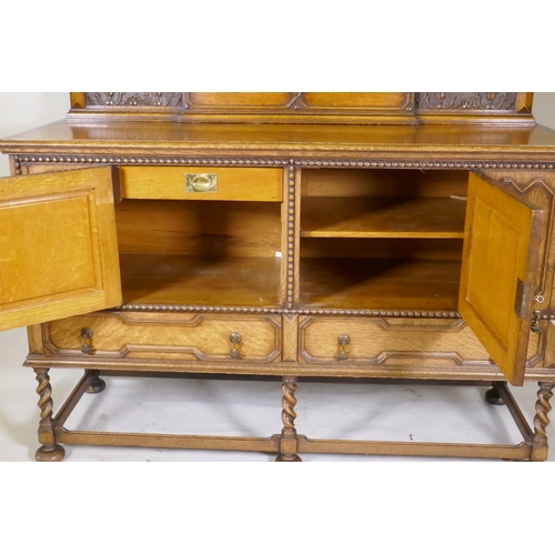 1039 - An early C20th oak Jacobean style mirror back sideboard, with two cupboards opening to reveal shelve... 