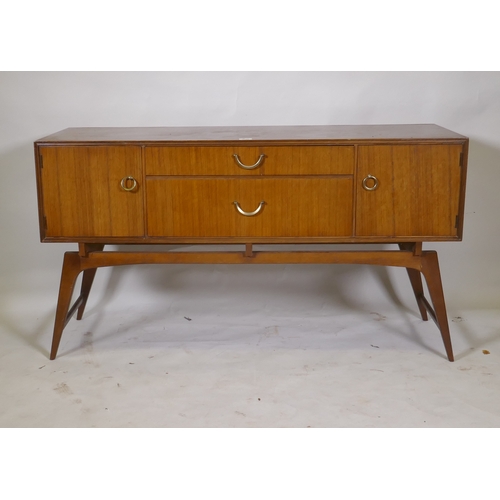 1042 - A mid century teak dressing table/low side cabinet, with two cupboards flanking two drawers, raised ... 