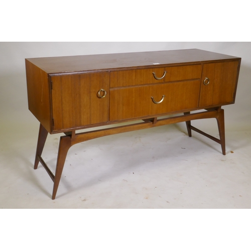 1042 - A mid century teak dressing table/low side cabinet, with two cupboards flanking two drawers, raised ... 