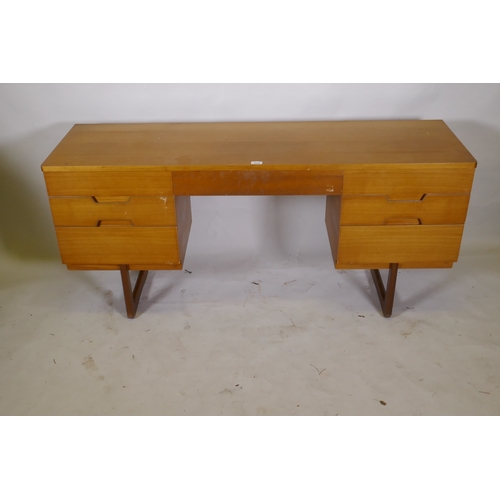 1049 - A mid century teak dressing table/side cabinet with seven drawers, raised on end supports, labelled ... 