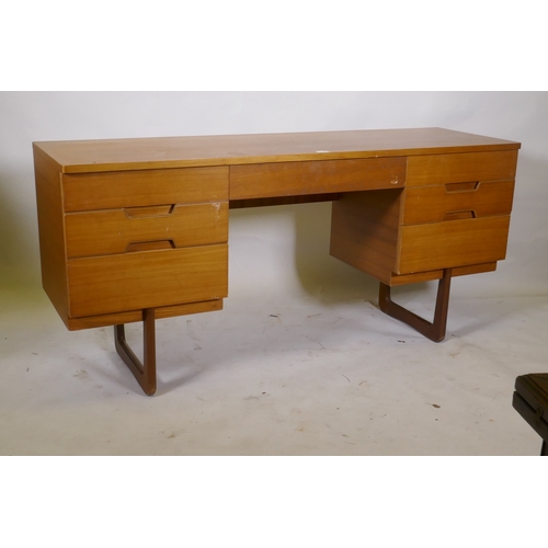 1049 - A mid century teak dressing table/side cabinet with seven drawers, raised on end supports, labelled ... 