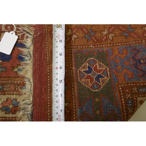 1054 - An antique Bergama carpet, with geometric designs on a terracotta coloured field and soft sheen to t... 