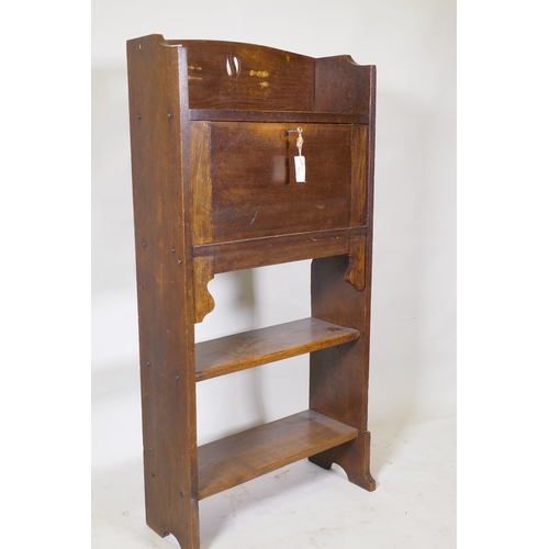 1058 - An Arts and Crafts oak bureau, with fall front and fitted interior over two open shelves, 61 x 22 x ... 