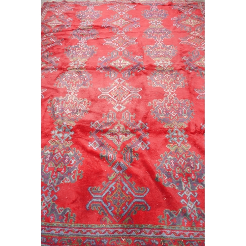 1061 - A full pile wool carpet with geometric designs on a red field, 290 x 385cm