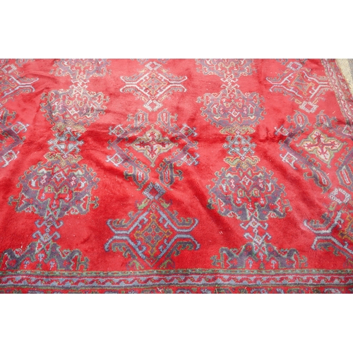 1061 - A full pile wool carpet with geometric designs on a red field, 290 x 385cm