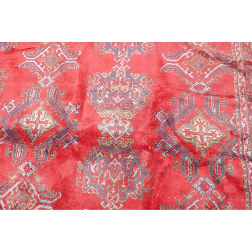 1061 - A full pile wool carpet with geometric designs on a red field, 290 x 385cm