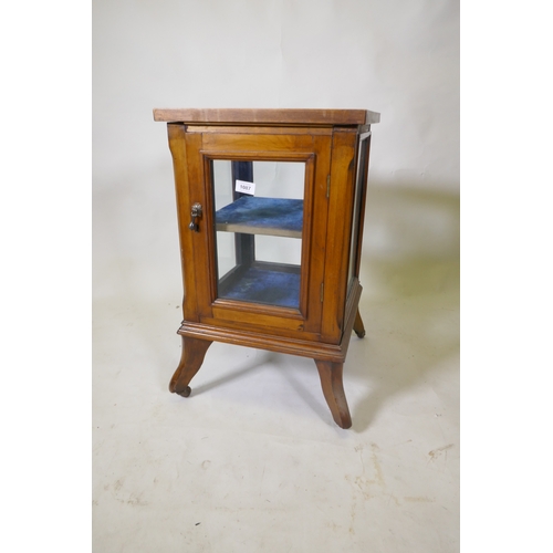 1087 - A small walnut vitrine with single door, raised on shaped supports with castors, 39 x 39 x 66cm