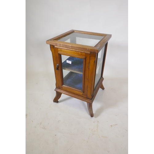 1087 - A small walnut vitrine with single door, raised on shaped supports with castors, 39 x 39 x 66cm