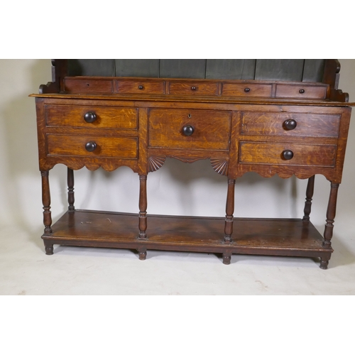 1092 - A Georgian oak potboard dresser, the upper section with enclosed delft rack under a shaped frieze, t... 