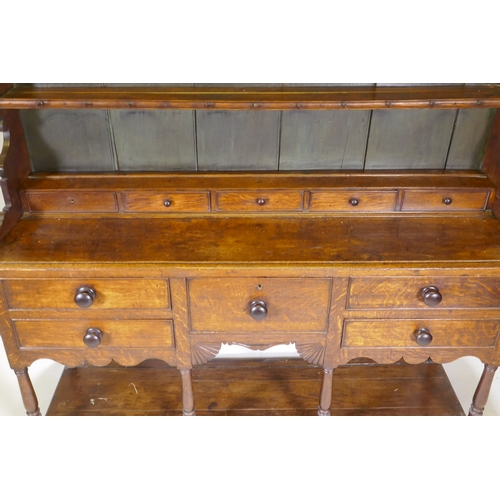 1092 - A Georgian oak potboard dresser, the upper section with enclosed delft rack under a shaped frieze, t... 