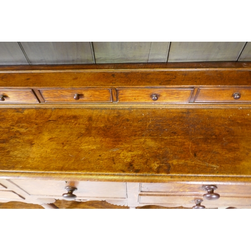 1092 - A Georgian oak potboard dresser, the upper section with enclosed delft rack under a shaped frieze, t... 