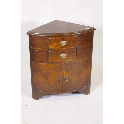 1095 - A bow fronted walnut corner cabinet, with two drawers over two cupboards, raised on bracket supports... 