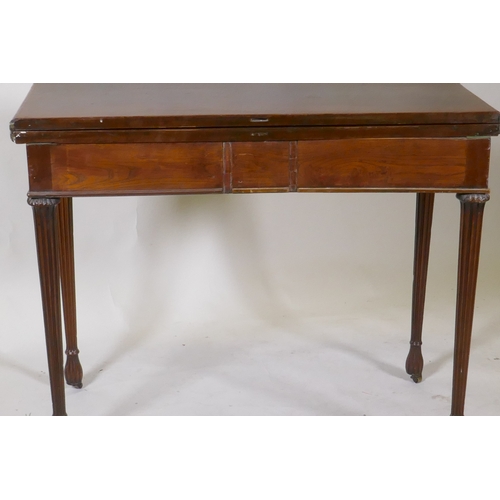 1097 - A Georgian mahogany fold over tea table, with single drawer and swan neck handles, raised on fluted ... 