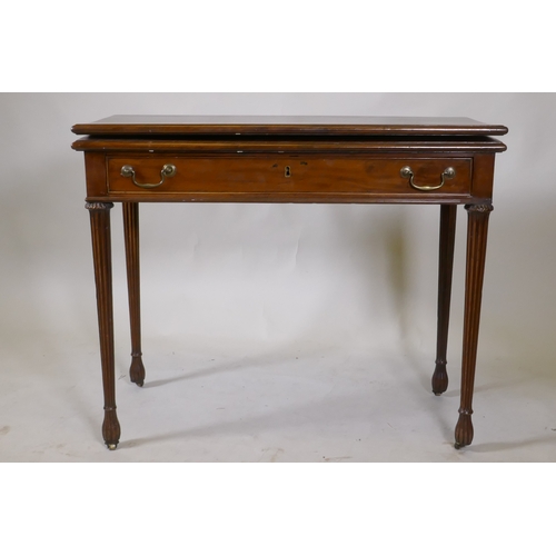 1097 - A Georgian mahogany fold over tea table, with single drawer and swan neck handles, raised on fluted ... 