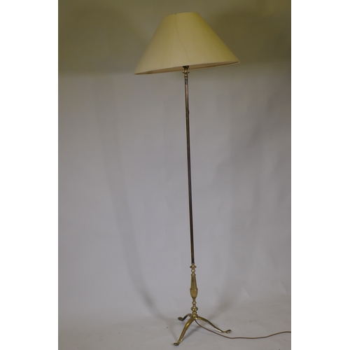 1101 - A vintage brass floor lamp raised on tripod supports, 150cm high