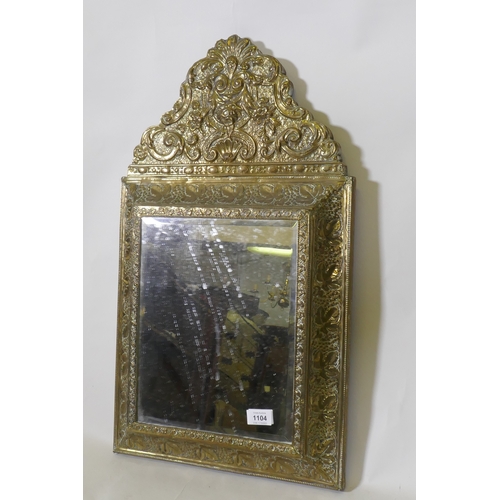 1104 - A C19th French brass cushion mirror, with grape and vine decoration, floral crest and inset bevelled... 