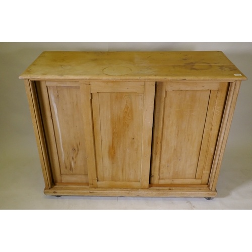 1106 - A C19th pine side cabinet with three sliding doors, on a plinth base with castors, 126 x 48 x 98cm