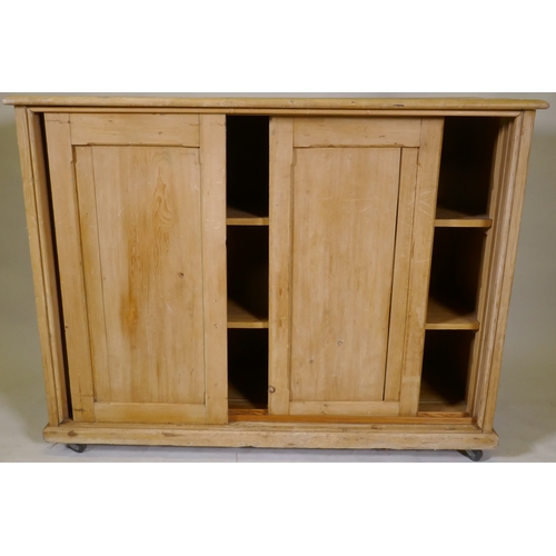 1106 - A C19th pine side cabinet with three sliding doors, on a plinth base with castors, 126 x 48 x 98cm