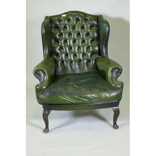 1147 - A green leather buttoned wingback armchair