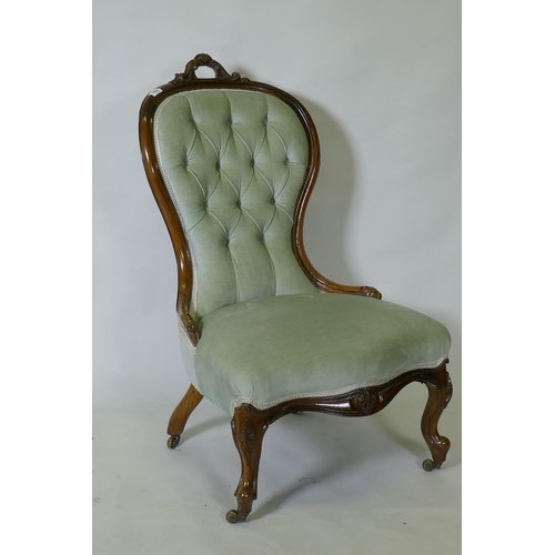 1152 - A Victorian carved walnut nursing chair, raised on cabriole supports with brass castors