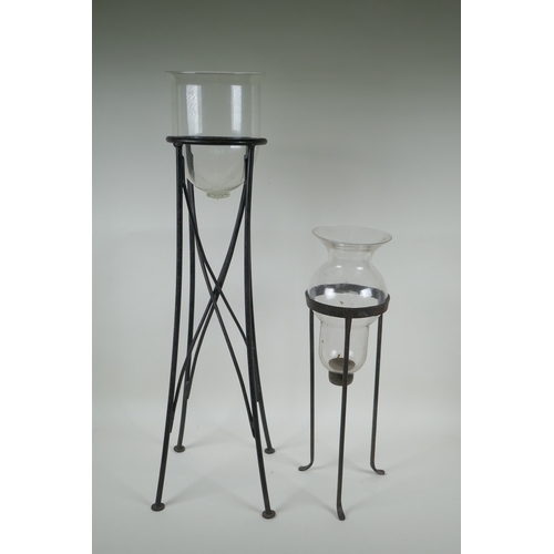 123 - A glass hurricane vase on a wrought iron stand, and another, largest 76cm high